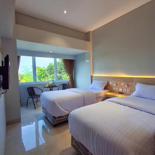a hotel room with two beds and a window at Hotel Kebon Kana Kaliurang in Kaliurang
