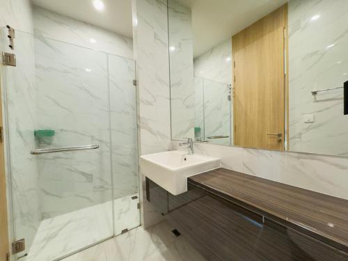 a white bathroom with a sink and a shower at Noble Bangkok Condo in Bangkok