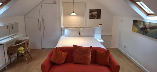 a bedroom with a large bed and a red couch at The Coach House Studio Apartment in Leamington Spa