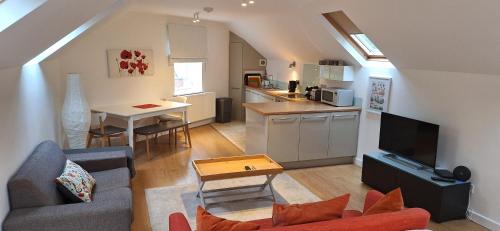 a living room with a couch a table and a kitchen at The Coach House Studio Apartment in Leamington Spa