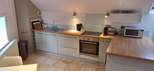 a kitchen with white cabinets and a counter top at The Coach House Studio Apartment in Leamington Spa
