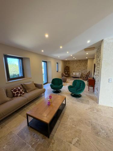 un salon avec un canapé et deux chaises vertes dans l'établissement Le Mas des Sources - 2 Piscines - by Zenlife, à Saint-André-dʼOlérargues