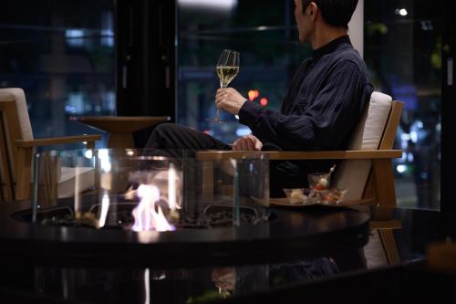 um homem sentado numa cadeira a beber um copo de vinho em The Royal Park Hotel Iconic Kyoto em Quioto