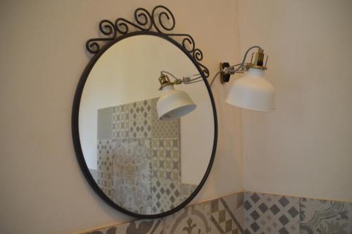 a mirror in a bathroom with two lights on a wall at B&B La Via di Casa in San Leone