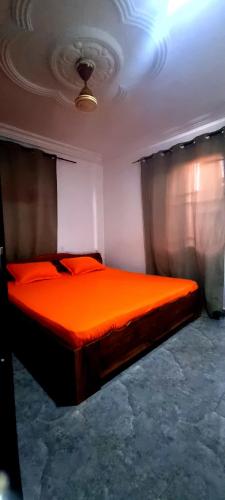 a bedroom with a bed with orange sheets and curtains at OSAK GUEST house in Midie