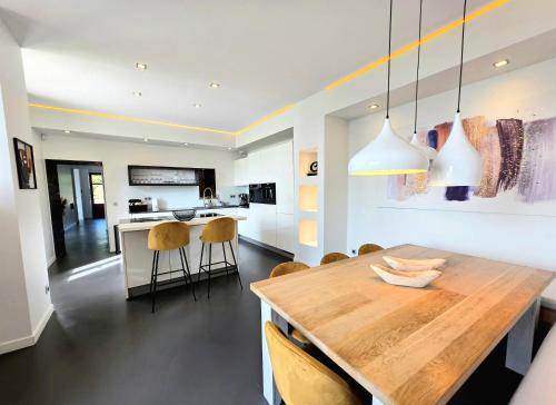 a kitchen and dining room with a wooden table and chairs at Villa Savoie - luxe et sérénité- piscine, sauna et jacuzzi - Annecy location prestige in Veyrier-du-Lac