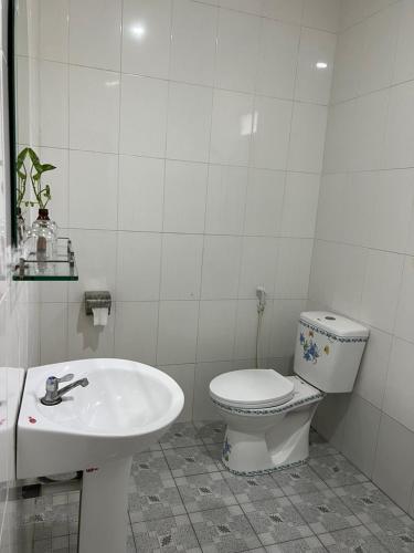 a white bathroom with a toilet and a sink at Nguyet Que Homestay & Tours in Ben Tre
