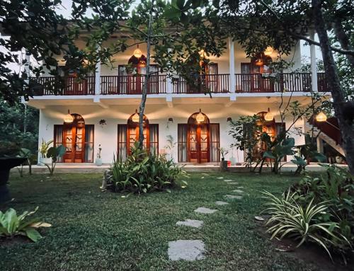 a large white house with a balcony at La Sirena Villa in Talpe