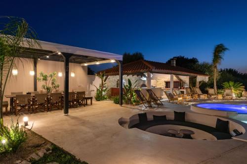 a patio with a table and a swimming pool at night at Vento Estivo Mansion in Pastida