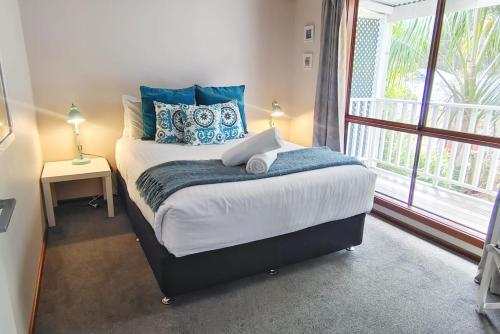 ein Schlafzimmer mit einem Bett mit blauen Kissen und einem Fenster in der Unterkunft Karri Birdsong Retreat in Margaret River Town