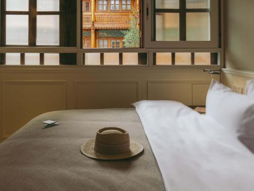 Sombrero en la parte superior de una cama con almohadas en Xianju Bieyuan Guesthouse Hotel, en Dali Shuanglang