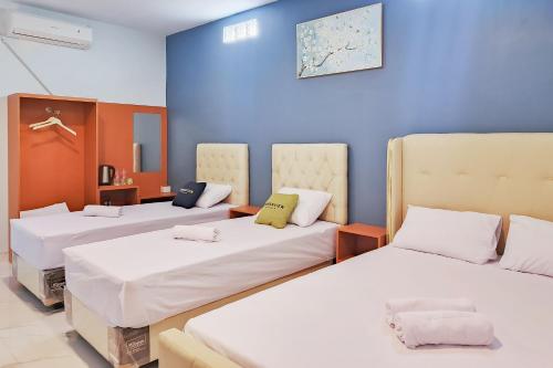 a room with three beds and a blue wall at Urbanview Hotel JD Luxury Brebes in Banjararja