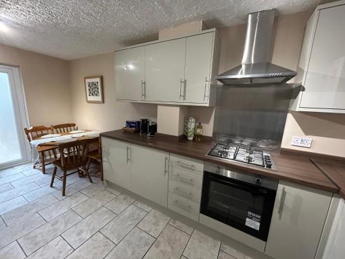 a kitchen with white cabinets and a stove top oven at Cosy Family Home in Lovely Stony Stratford in Stony Stratford