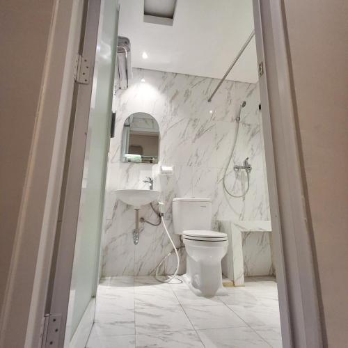 a white bathroom with a toilet and a sink at Hotel Kebon Kana Kaliurang in Kaliurang