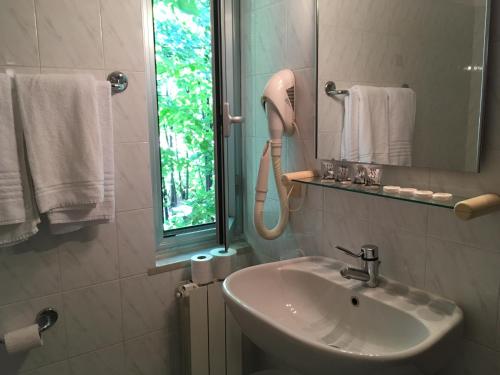 W łazience znajduje się umywalka, lustro i ręczniki. w obiekcie Hotel Annunziata w mieście Massa