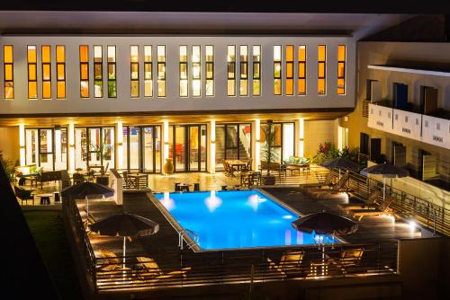 a swimming pool in front of a building at night at ONOMO Hotel Lomé in Lomé