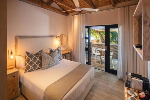 a bedroom with a bed and a patio with a table at The Bungalow in Plettenberg Bay
