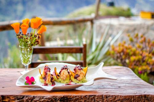 a plate of food on a wooden table with flowers at La Granja del Colca in Cabanaconde
