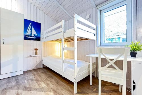 a bunk bed in a room with a desk and a window at Schatzkiste - Dorf Ferienhaus 18 in Priwall