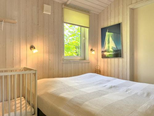 a bedroom with a bed and a window and a crib at Schatzkiste - Dorf Ferienhaus 08 in Priwall