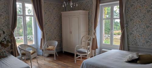 una camera con un letto e due sedie e finestre di Le Manoir du Châtelier a Bressuire