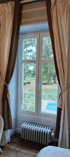 a bedroom with two windows and a radiator in front at Le Manoir du Châtelier in Bressuire