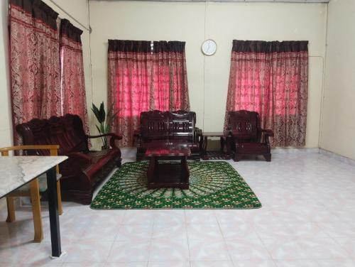 a living room with chairs and a green rug at Homestay Haji Hamid in Pantai Cenang