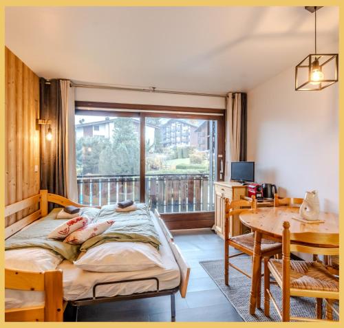 a bedroom with a bed and a table and a window at Le Paradisio I Studio I Morzine in Morzine