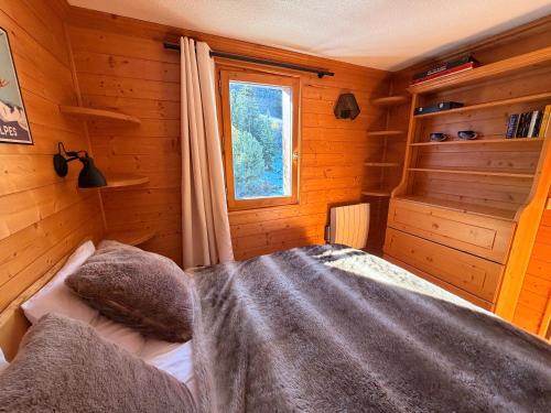 une chambre avec un lit dans une cabane en bois dans l'établissement Méribel Mottaret - Duplex - Plein sud - Pied des pistes, à Les Allues