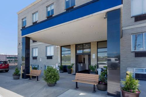 a building with two benches in front of it at Avion Inn Near LGA Airport, an Ascend Collection Hotel in Queens