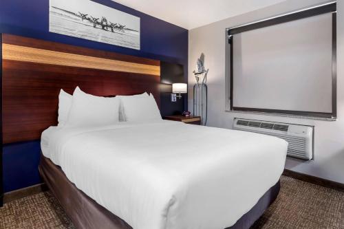 a large bed in a hotel room with a large screen at Avion Inn Near LGA Airport, an Ascend Collection Hotel in Queens