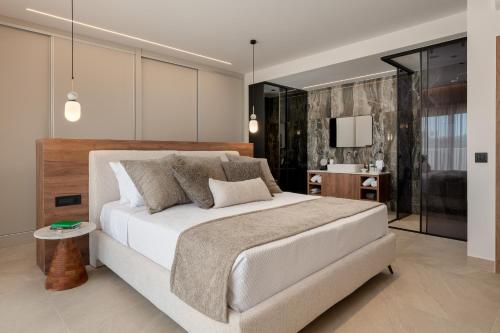 a bedroom with a large white bed and a bathroom at Lanik Luxury Pool Villa in Afantou