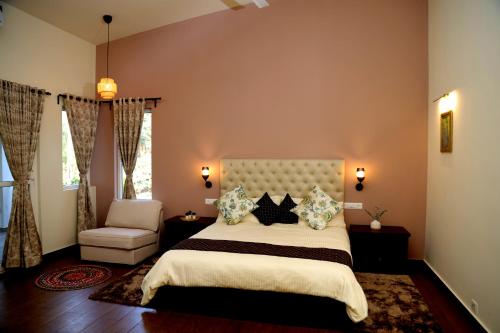 a bedroom with a large bed and a chair at Tranquility Home Stay Coorg in Kutta