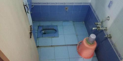 Un baño con suelo de baldosas azules y un inodoro. en Srusti Residency Mysore, en Jāmb