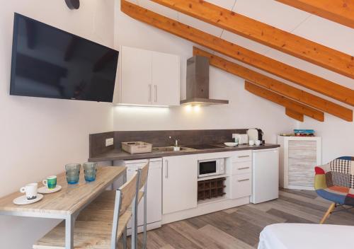 Una cocina con gabinetes blancos y una mesa de madera. en Apartamentos Al Andalusí, en Denia