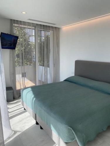 a bedroom with a green bed and a window at Velar Apartment Suites in Lignano Sabbiadoro