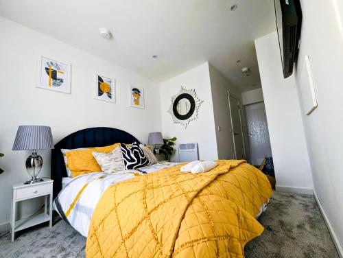 a bedroom with a bed with a yellow comforter at YSquared studio in Falkirk