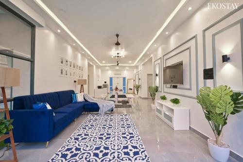 a living room with a blue couch and a tv at EKOSTAY Luxe - Ivory Coast Villa in Alibaug