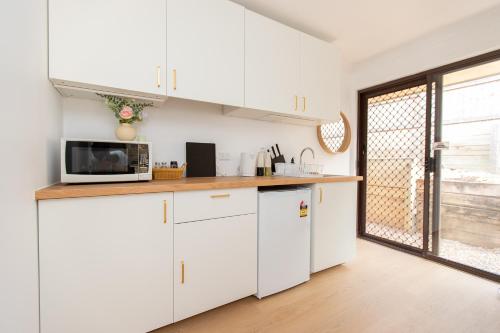 a kitchen with white cabinets and a microwave at Cozy Studio Suite in House - Private Kitchen Bath in Rochedale