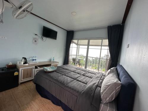 una camera da letto con un letto e una grande finestra di สเตชั่นภูทับเบิก-บ้านดาดฟ้าทะเลหมอก a Ban Tha Kok Hai