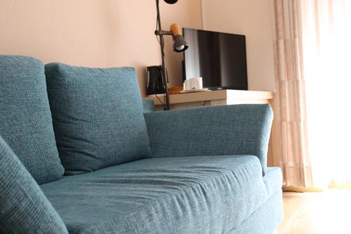 トリッテンハイムにあるGästehaus Weingut Heribert Bochのリビングルーム(青いソファ、テレビ付)