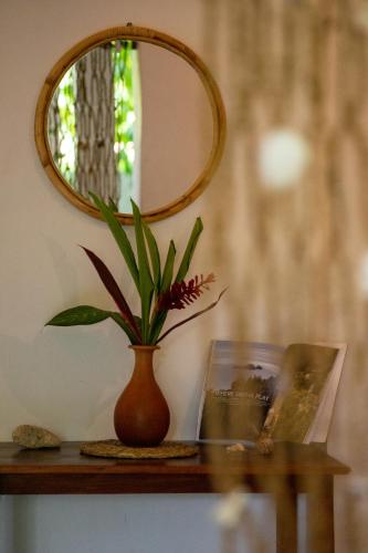 a plant in a vase on a table with a mirror at Drifter - Rooms & Food in Midigama East