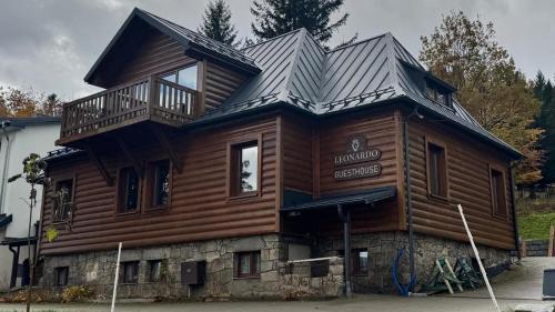 een grote houten hut met een balkon erboven bij Leonardo Guesthouse in Świeradów-Zdrój