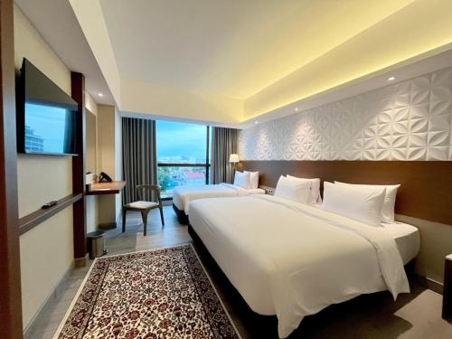 a hotel room with two beds and a flat screen tv at The Jogja Malioboro Hotel and Conference Center in Yogyakarta