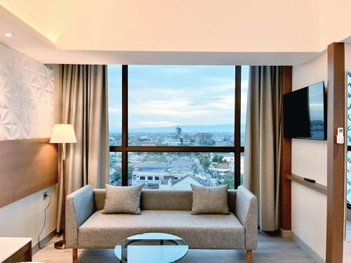 a living room with a couch and a large window at The Jogja Malioboro Hotel and Conference Center in Yogyakarta
