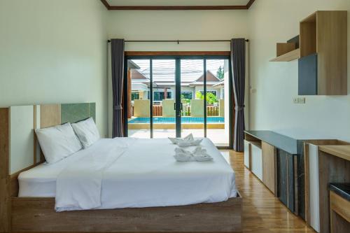 a bedroom with a bed and a view of a pool at ทองสุข Pool Villa 3 ห้องนอน in Ban Huai Thalaeng Phan