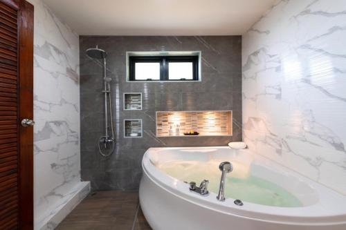 a white tub in a bathroom with a shower at ทองสุข Pool Villa 3 ห้องนอน in Ban Huai Thalaeng Phan