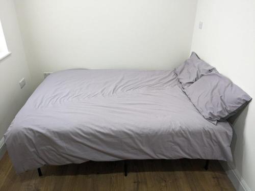 a bed with white sheets and pillows in a room at Stylish Self Contained Unit - High Wycombe in High Wycombe