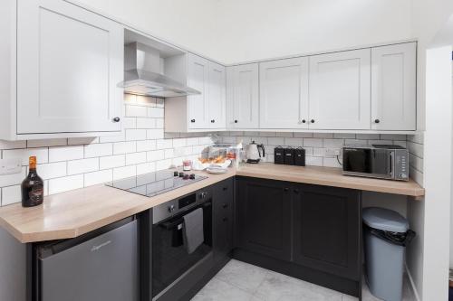 eine Küche mit weißen Schränken und einer Holzarbeitsplatte in der Unterkunft Albert's Cottage, Dorset in Blandford Forum