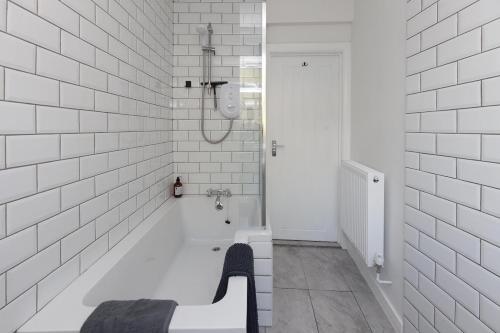 ein weiß gefliestes Badezimmer mit einer Sitzbank und einer Dusche in der Unterkunft Albert's Cottage, Dorset in Blandford Forum